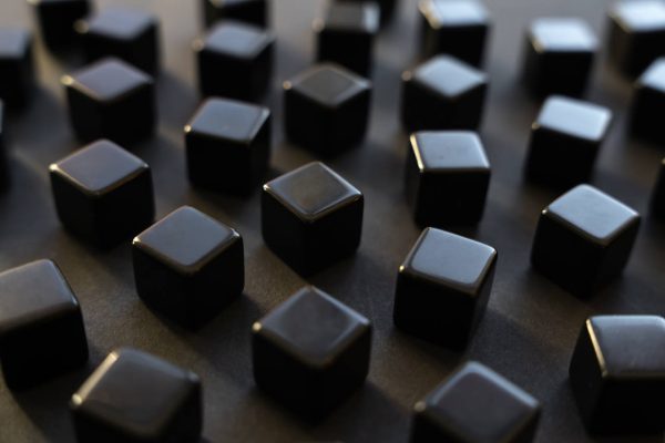 Black blocks on a dark background. Scattered cubes. Abstraction, field blur. Simplicity and elegance. Solidity, shine.